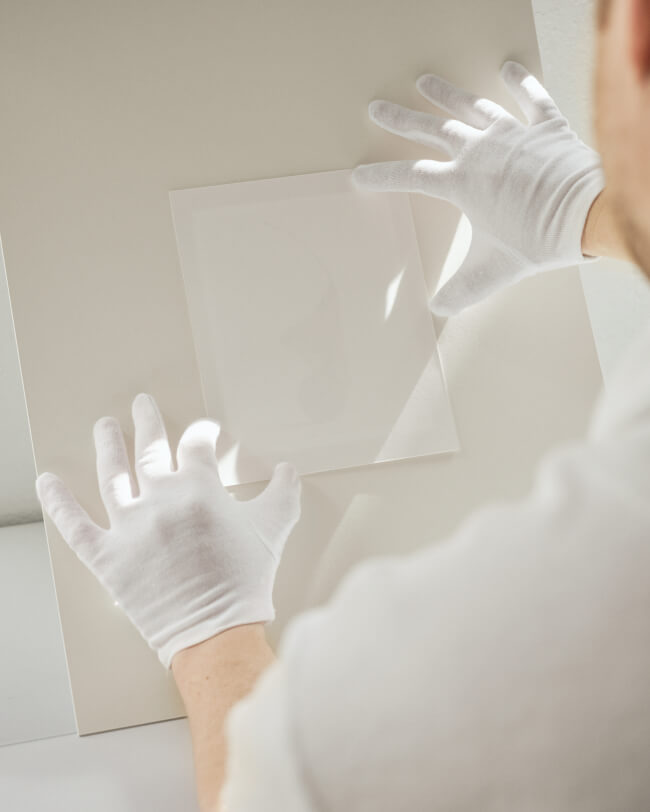 Art photograph being mounted on a passepartout by a man in white cotton gloves